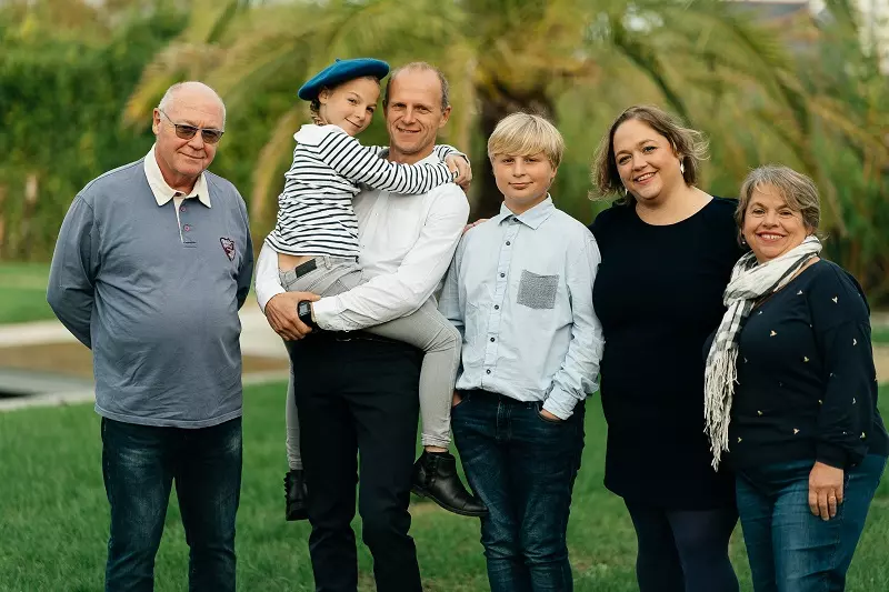 Photographe professionnelle en lumière naturelle à Rennes, appareil photo Lumix à la main, souriant avec authenticité en extérieur
