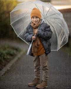 un jeune garçon sous la pluie avec une parapluie