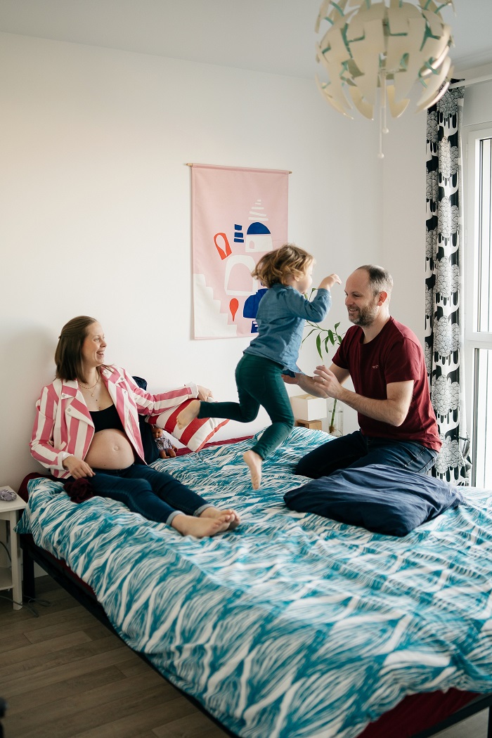 Shooting photo famille à domicile, parents avec l'enfant qui saute sur un lit