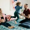 Shooting photo famille à domicile, parents avec l'enfant qui saute sur un lit