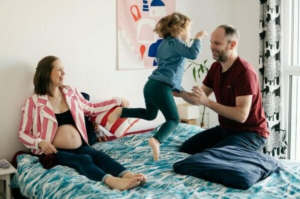 Shooting photo famille à domicile, parents avec l'enfant qui saute sur un lit