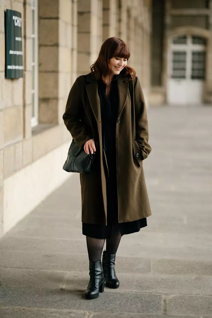 Femme habillé en manteau souriante regardant le sol