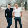 Photographe professionnelle en lumière naturelle à Rennes, appareil photo Lumix à la main, souriant avec authenticité en extérieur